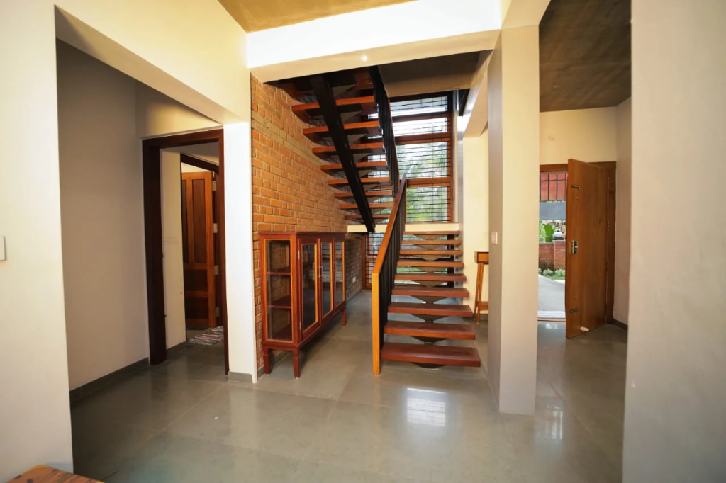 Architectural floating teak staircase and brick wall at Norah Retreat